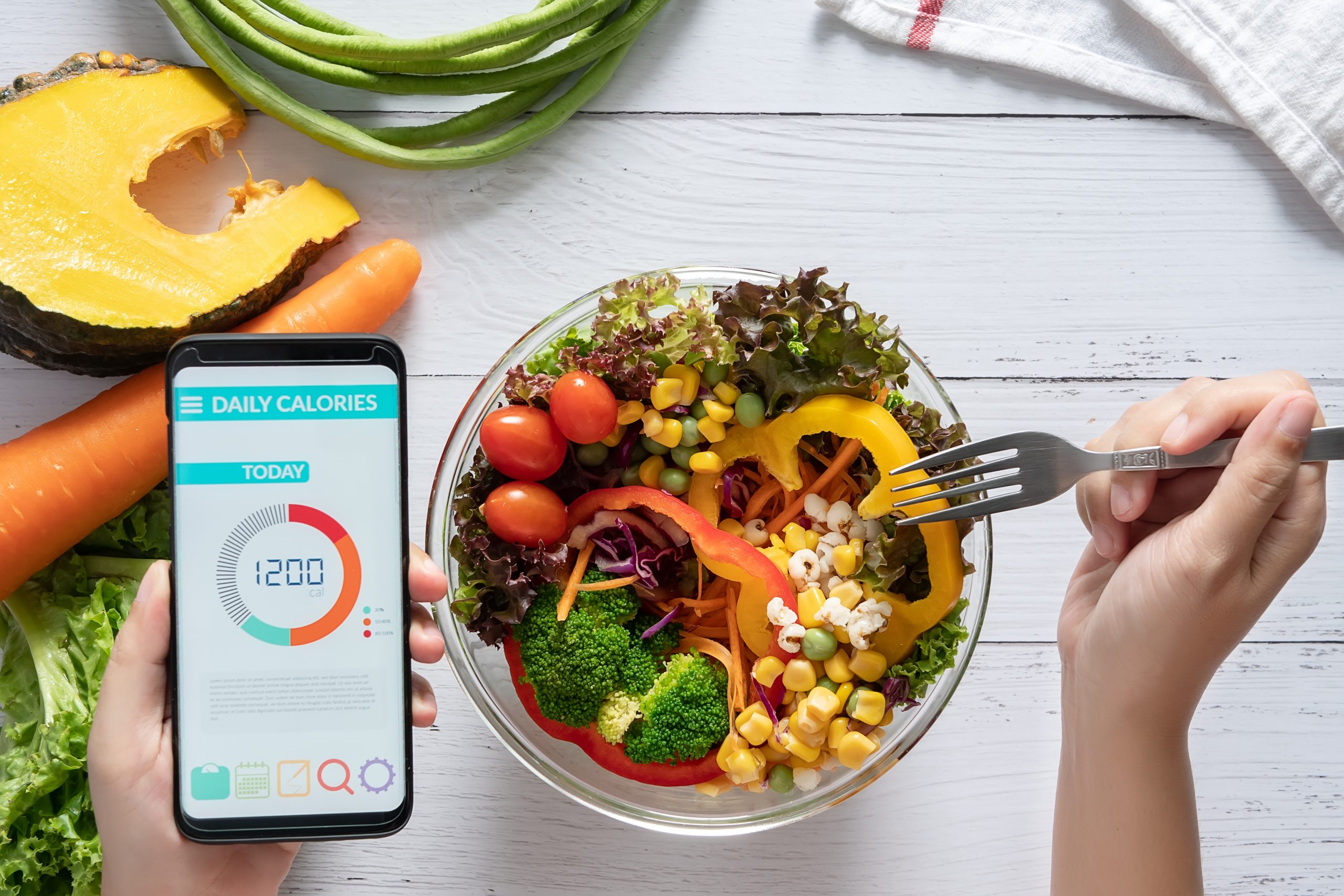 TDEE Calculator person counting calories on their phone will eating healthy food